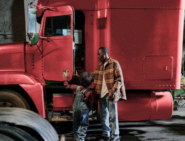 Image of truck driver with kid standing next to red semi
