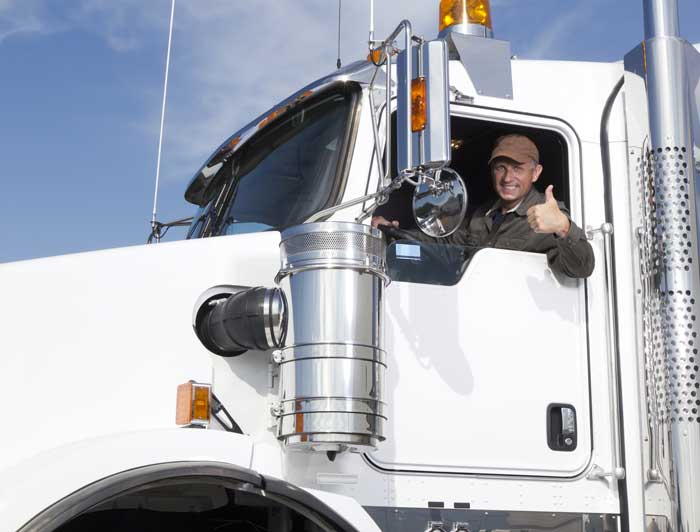 Trucker giving a thumbs up in his truck cab.