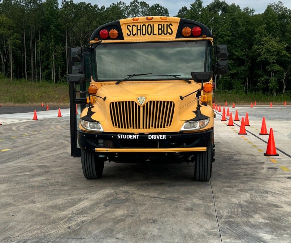 Front view of a school bus parked in training yard surrounded by cones