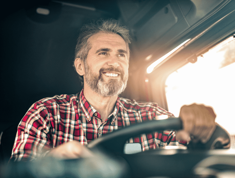 Picture of middle aged man with a healthy lifestyle sitting behind the wheel of an 18-wheeler smiling