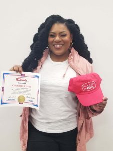 Female GDA graduate holding CDL certificate and GDA hat