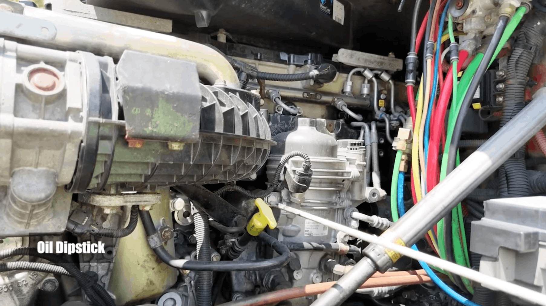 Stick pointing to oil dipstick in front hood of semi truck